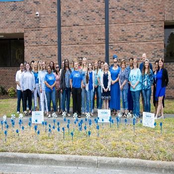 DSS employees and community partners stand behind their pinwheel garden on Friday, April 4, 2025.